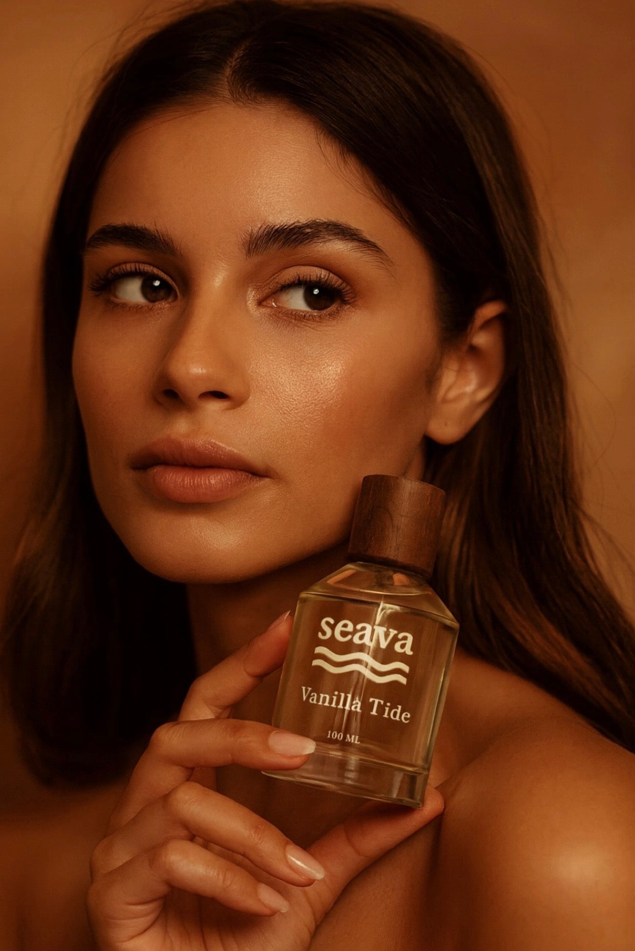 Woman holding a 'seava Vanilla Tide' perfume bottle against a warm-toned background
